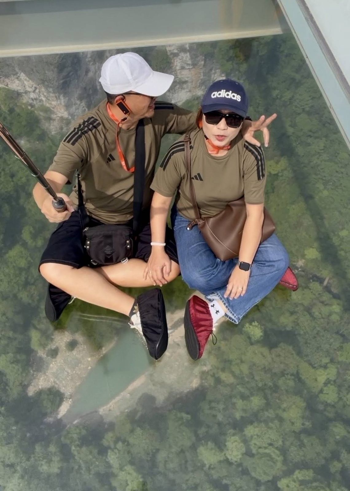 Travellers on a glass walkway high above the forest, wearing the shoe covers provided